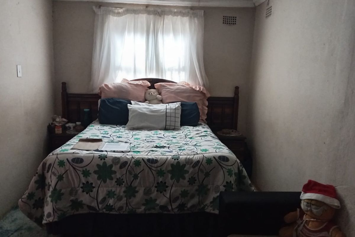 A compact bedroom featuring a timber-framed bed, standard window with curtains, and integrated wall ventilation vents.