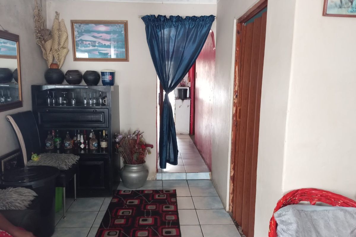 Interior view of a living area featuring tiled flooring, a wooden folding door, and a transition space leading to a secondary room.