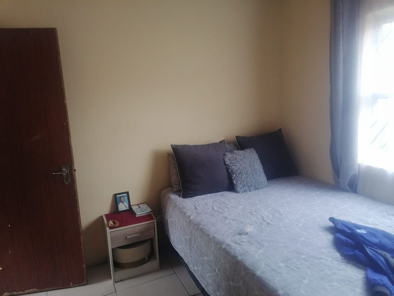A compact bedroom featuring tiled flooring and a window with security bars, requiring minor cosmetic updates to improve the overall finish.