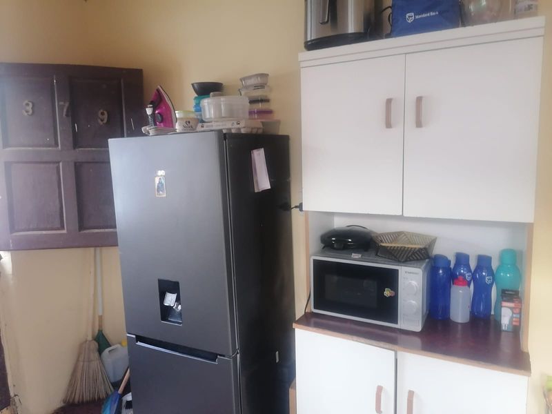 A compact kitchen area featuring white built-in cabinetry, a laminate countertop, and a built-in microwave space.