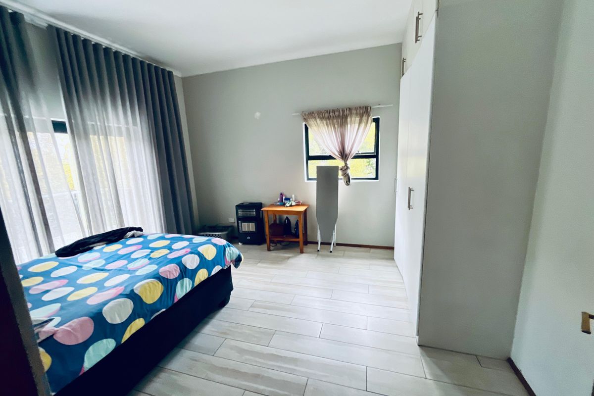 A well-lit bedroom featuring modern tiled flooring, built-in cupboards, and a sliding door leading to an outdoor area.
