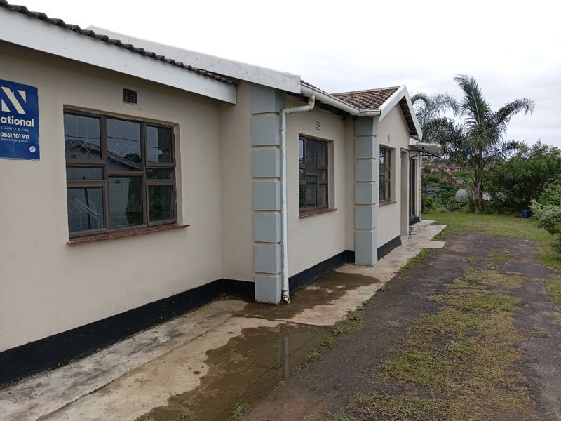 Rear exterior view of the house featuring a tiled roof, concrete pathway, and security bars on the windows.