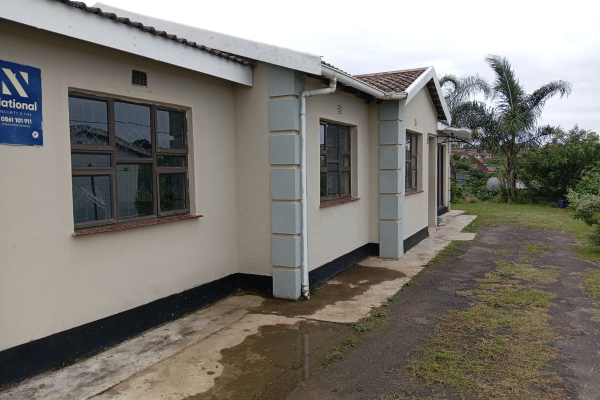 Rear exterior view of the house featuring a tiled roof, concrete pathway, and security bars on the windows.
