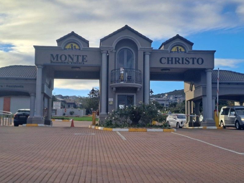 The main entrance gatehouse for the Monte Christo estate, featuring a paved driveway, security access control, and a prominent architectural facade.
