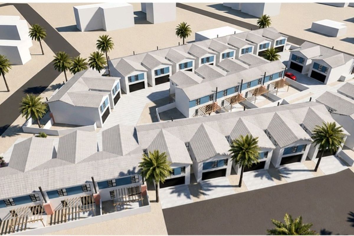 Aerial view of a townhouse complex development featuring multiple units with pitched roofs, garages, and paved driveways.