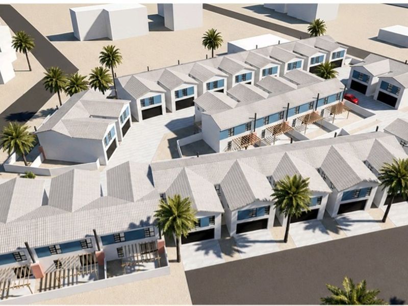 Aerial view of a townhouse complex development featuring multiple units with pitched roofs, garages, and paved driveways.
