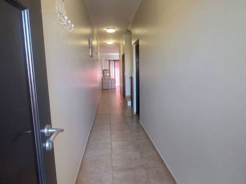 A clean, neutral-toned hallway featuring tiled flooring and multiple internal access points, providing a functional transition space within the townhouse.