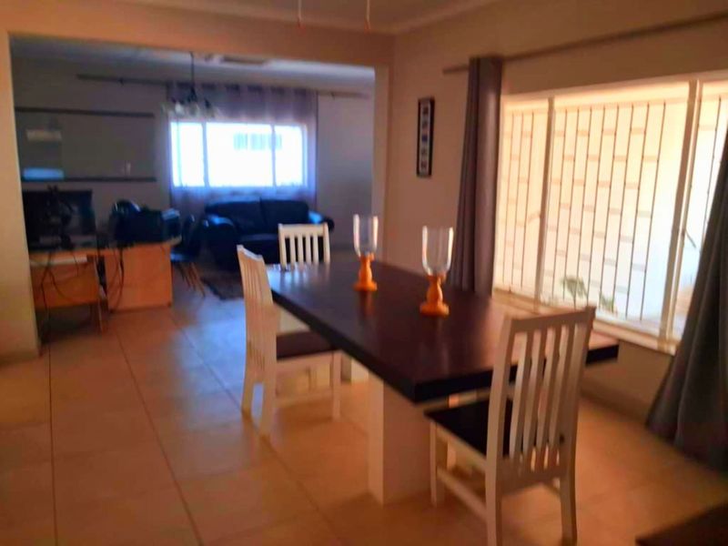 An open-plan living and dining area featuring tiled flooring and large windows that provide natural light to the space.