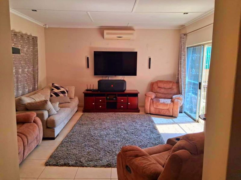 A comfortable living room featuring tiled flooring, a wall-mounted air conditioning unit, and a sliding glass door providing access to the exterior.