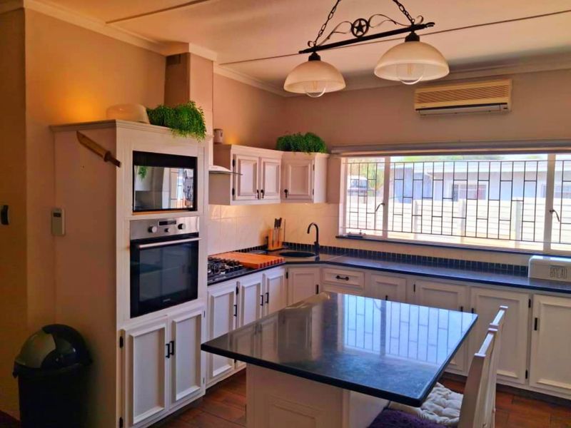 A well-maintained kitchen featuring white cabinetry, granite countertops, a central island, built-in oven and microwave, and a split-system air conditioner.