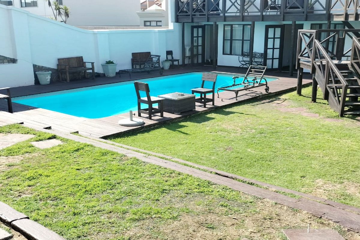 Outdoor pool area featuring a swimming pool, timber decking, and a wooden staircase leading to an upper balcony level.