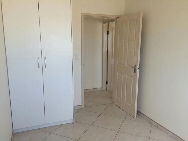 An empty bedroom featuring tiled flooring and a built-in wardrobe, providing a clean and neutral space ready for personalization.