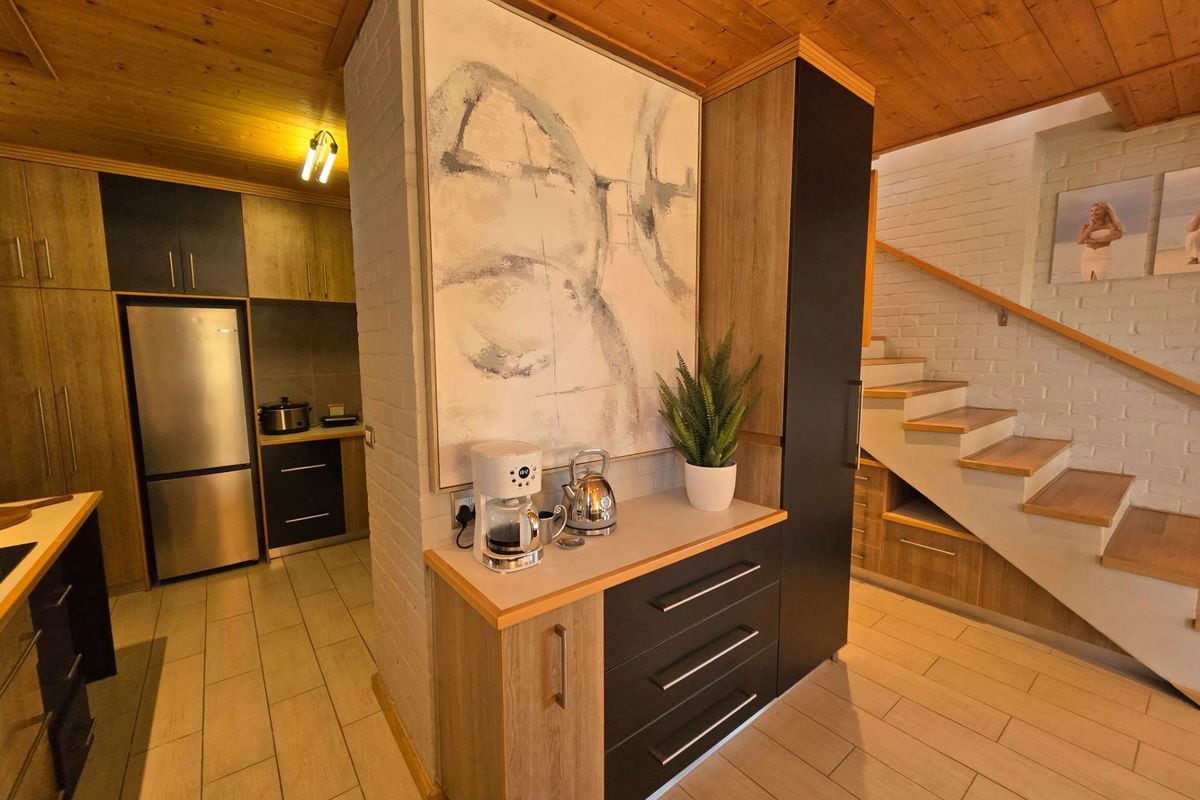 Modern kitchen featuring timber ceilings, sleek built-in cabinetry, and integrated under-stair storage, creating a functional and stylish open-plan living space.