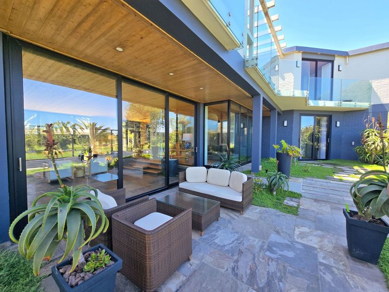 A modern covered patio featuring stone paving, timber ceiling, and large sliding glass doors that provide seamless indoor-outdoor flow.