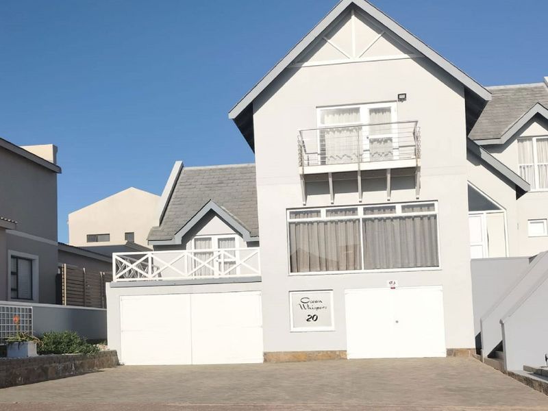 Front elevation of a multi-story residential property featuring a paved driveway, double garage, and upper-level balcony with gabled roof architecture.