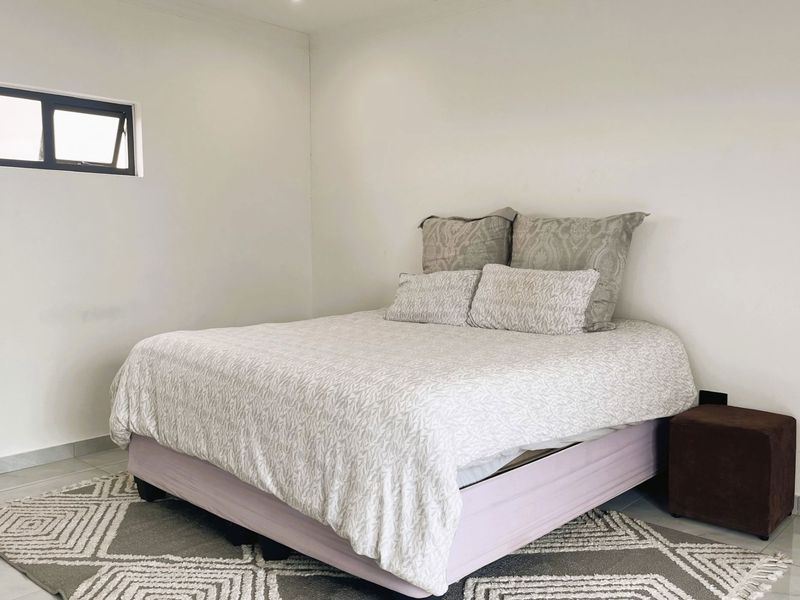 A simple bedroom featuring tiled flooring and a top-hung window, providing a neutral space ready for personalization.
