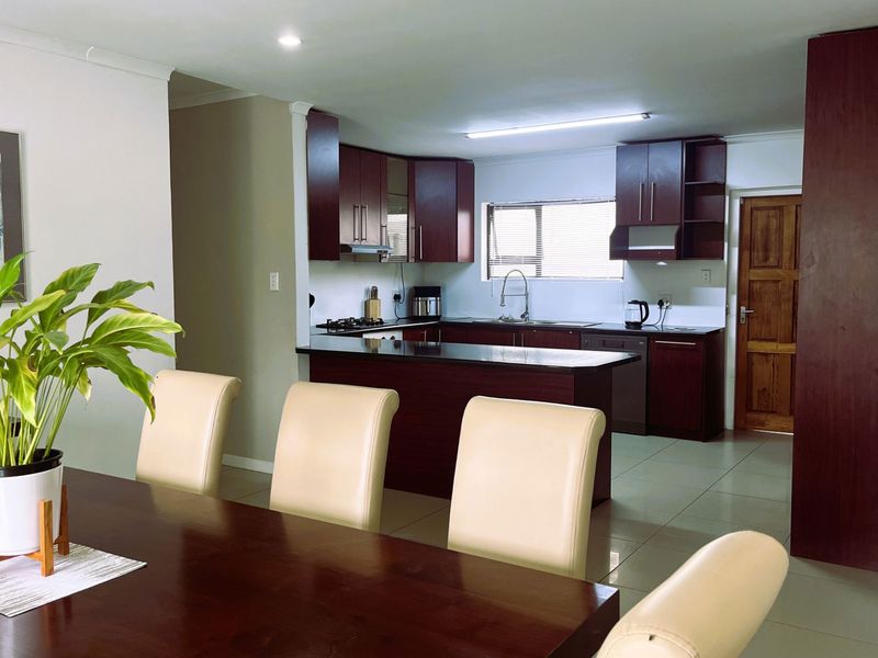 Open-plan kitchen featuring dark wood cabinetry, granite countertops, and tiled flooring, seamlessly integrated with the dining area.