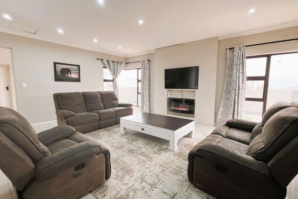 A well-maintained living room featuring recessed downlights, tiled flooring, and a built-in fireplace with an integrated television mount.
