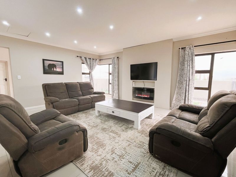 A well-maintained living room featuring recessed downlights, tiled flooring, and a built-in fireplace with an integrated television mount.