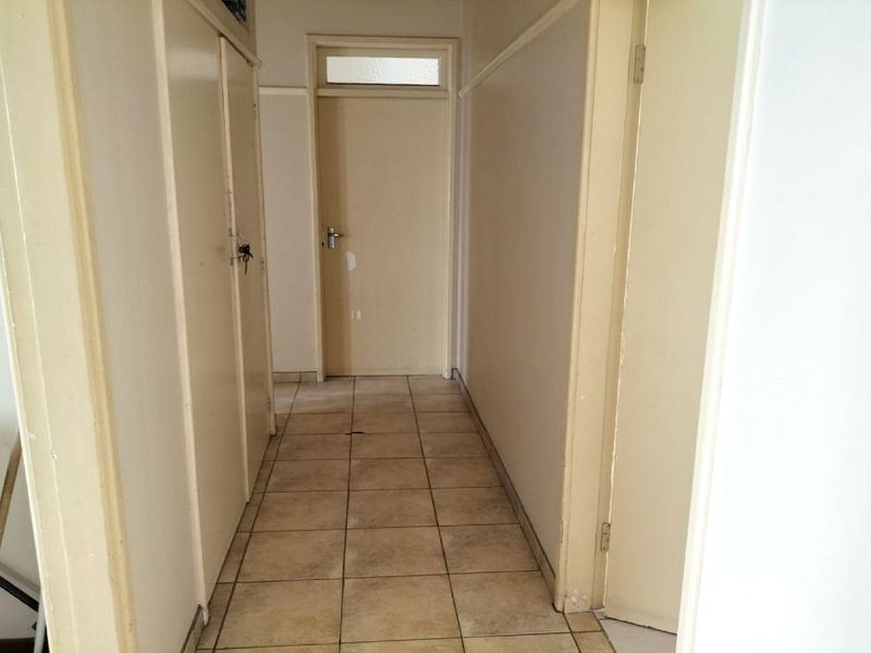 A functional hallway featuring tiled flooring, built-in storage cupboards, and multiple interior doors with transom windows.