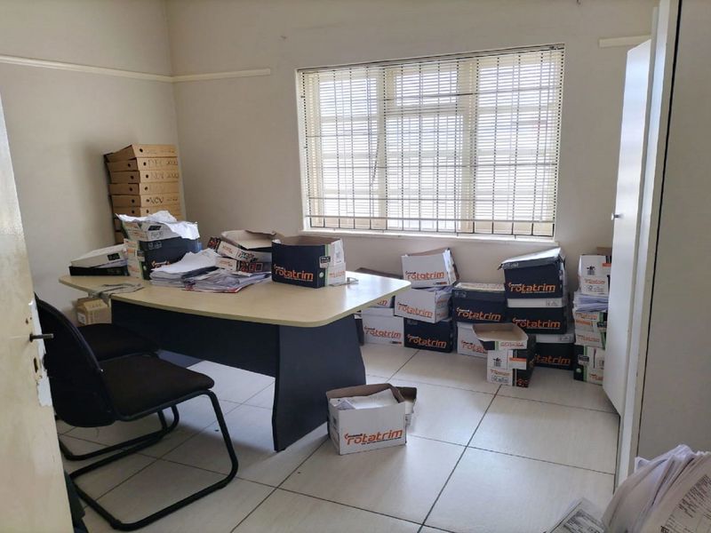 A functional office space featuring tiled flooring and a window with venetian blinds, suitable for a professional work environment.
