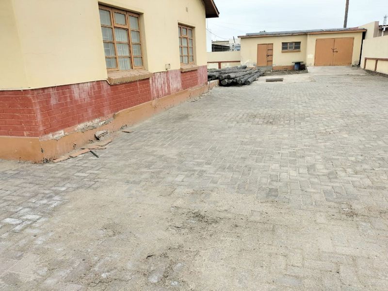 Rear exterior view showing a paved yard area, brick building facade, and detached garage structure.