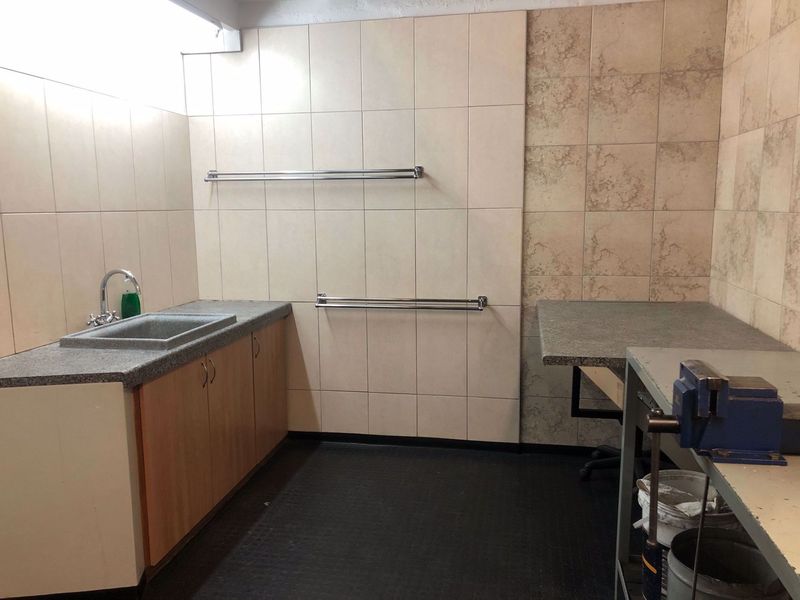 A functional utility space featuring built-in cabinetry, a sink, and tiled wall finishes, suitable for workshop or maintenance tasks.