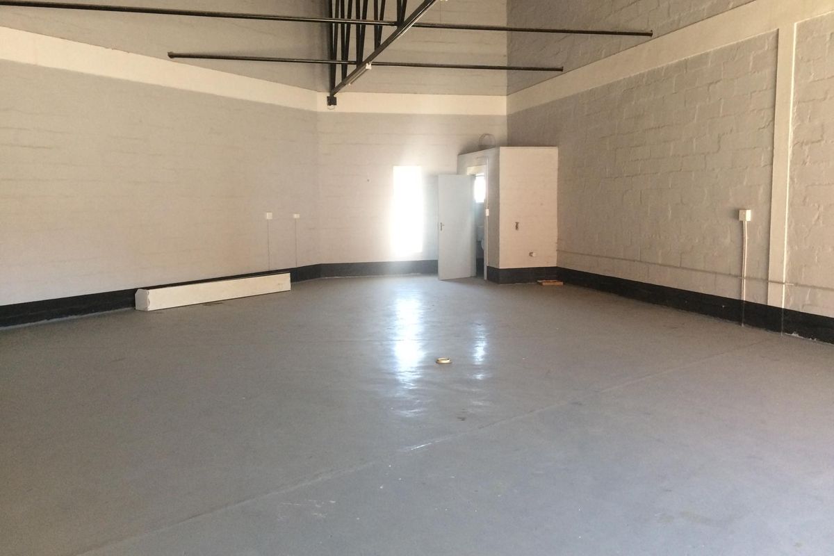 Spacious industrial utility area featuring high ceilings with exposed steel trusses, painted block walls, and a durable epoxy-coated concrete floor.
