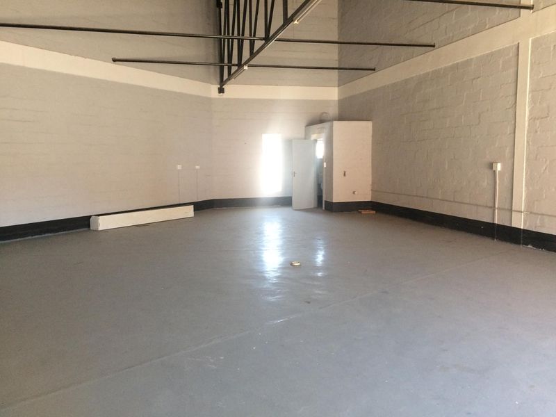 Spacious industrial utility area featuring high ceilings with exposed steel trusses, painted block walls, and a durable epoxy-coated concrete floor.