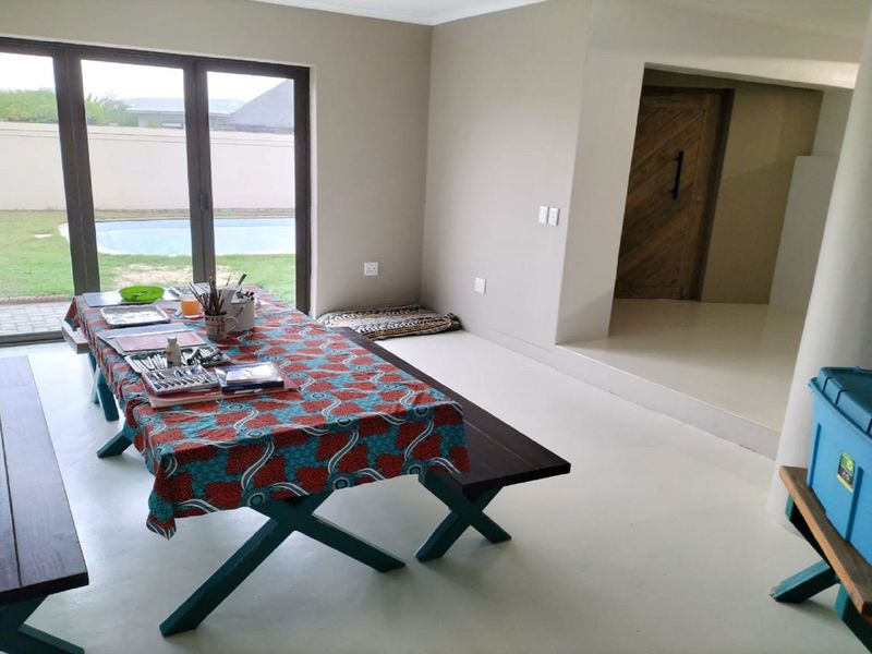Open plan living area featuring tiled flooring, neutral walls, and large sliding glass doors providing direct access to the outdoor pool area.