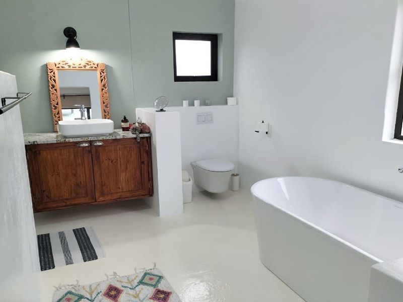 Modern bathroom featuring a freestanding bathtub, wall-hung toilet, and a rustic wooden vanity with a vessel sink and granite countertop.