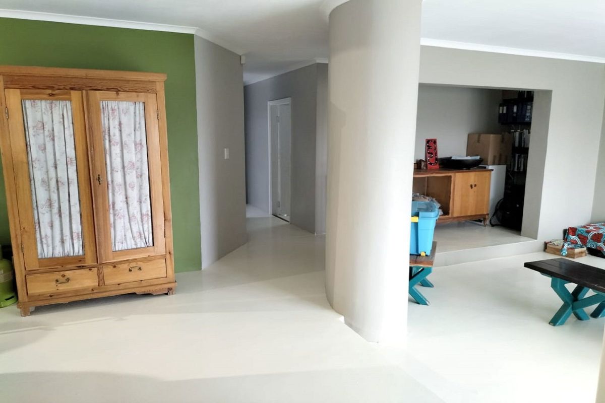 A living area featuring a distinctive curved structural column, painted concrete flooring, and a recessed alcove space.
