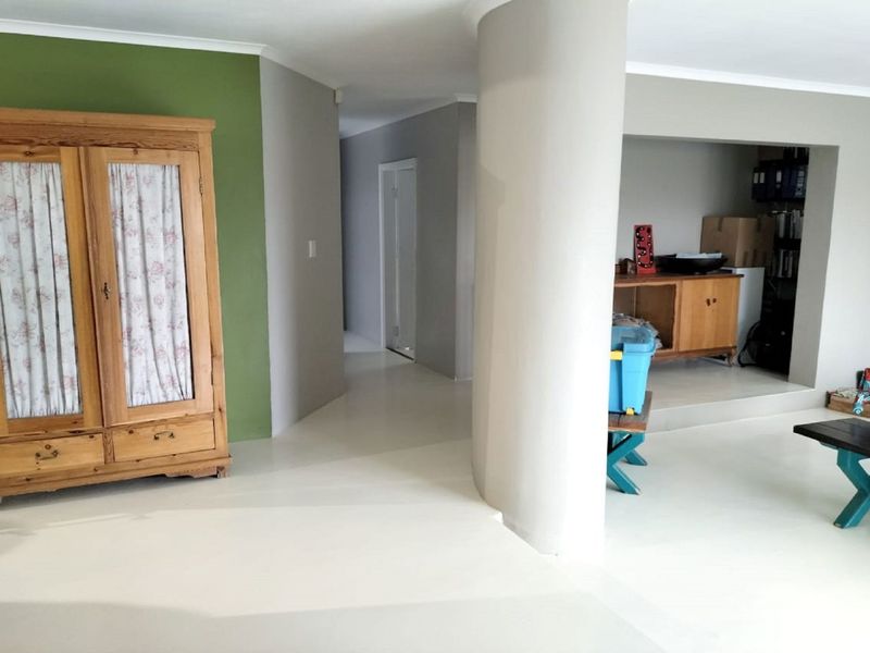 A living area featuring a distinctive curved structural column, painted concrete flooring, and a recessed alcove space.