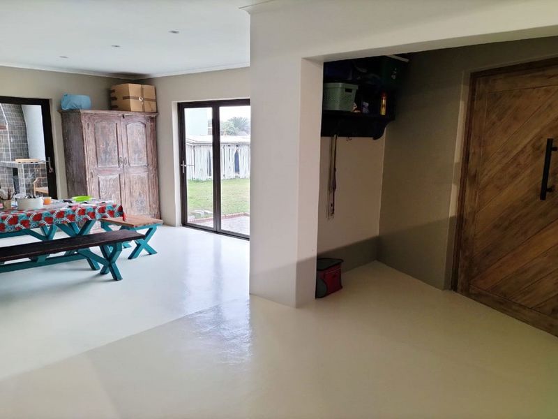 Open plan living area featuring smooth epoxy flooring, recessed lighting, a feature wooden barn door, and sliding glass doors providing access to the rear garden.