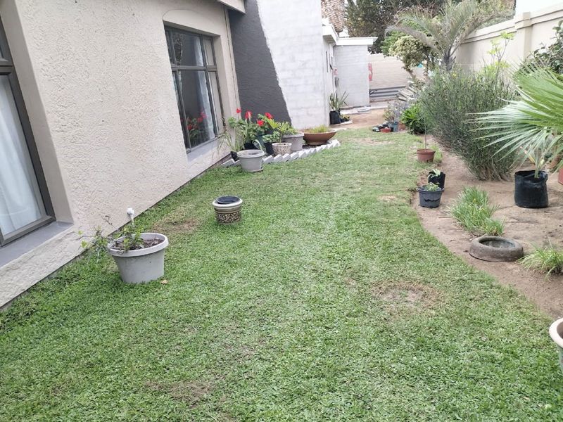 A rear garden area featuring a lawn, boundary wall, and unfinished exterior wall plastering, offering potential for landscaping and exterior improvement.