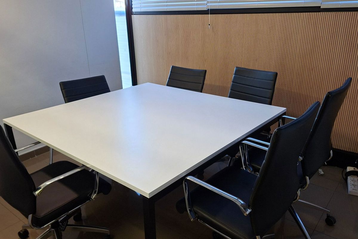 A functional office meeting room featuring modern slatted wood wall paneling, tiled flooring, and integrated window blinds.