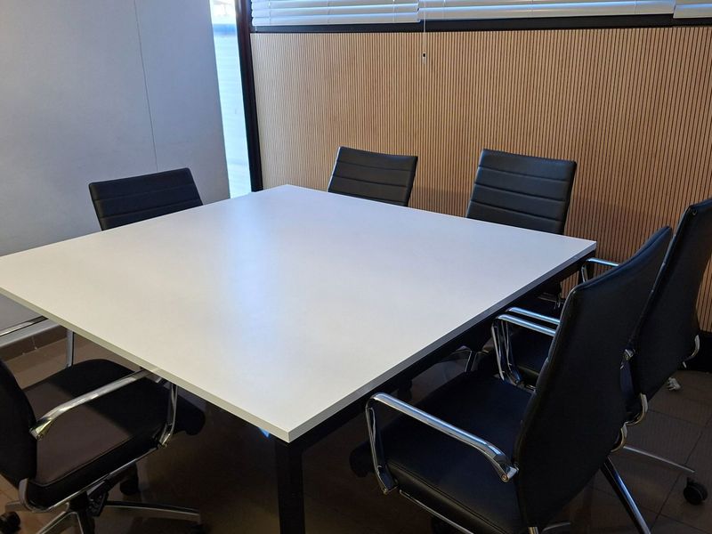 A functional office meeting room featuring modern slatted wood wall paneling, tiled flooring, and integrated window blinds.