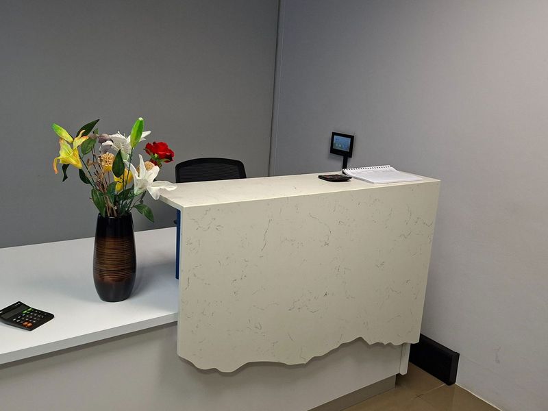 A professional office reception area featuring a modern built-in desk with a stone countertop.