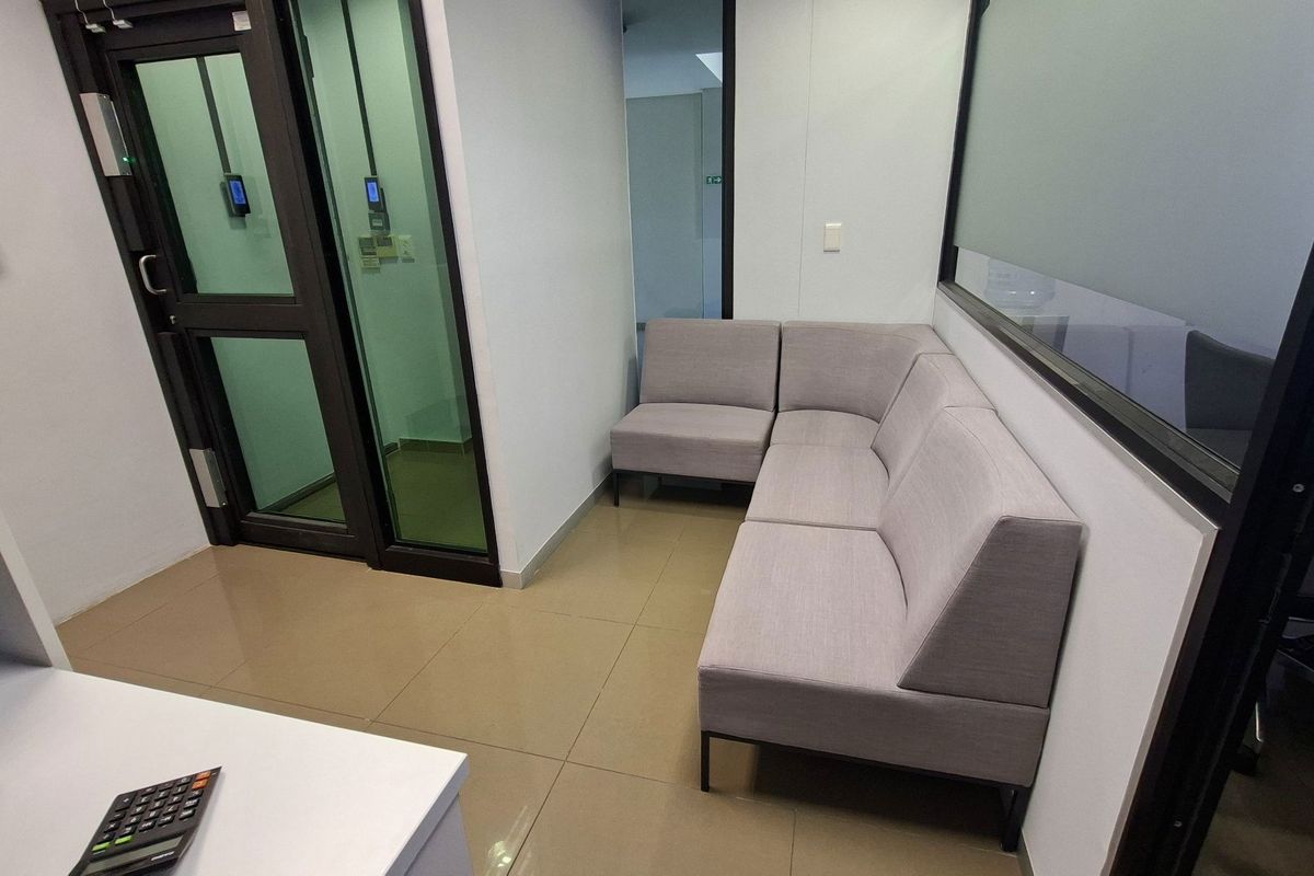 A modern office waiting area featuring tiled flooring, glass partitions, and integrated access control systems.