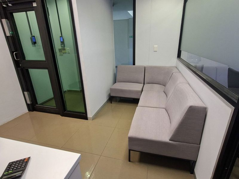 A modern office waiting area featuring tiled flooring, glass partitions, and integrated access control systems.