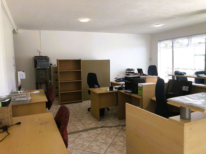 A functional office space featuring tiled flooring, recessed ceiling lighting, and large windows providing natural light.