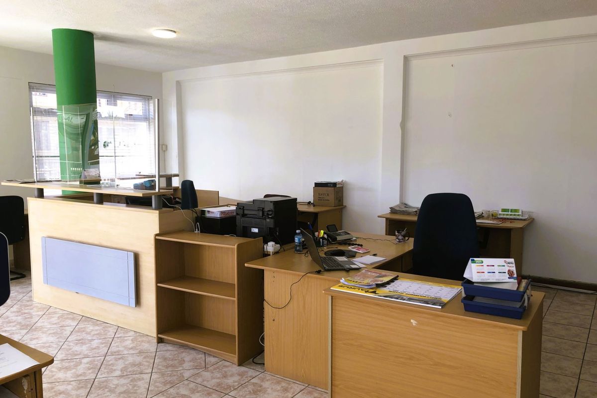 A functional office space featuring ceramic tile flooring, a reception counter, and built-in shelving units, suitable for a professional work environment.