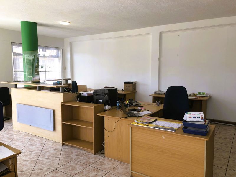 A functional office space featuring ceramic tile flooring, a reception counter, and built-in shelving units, suitable for a professional work environment.
