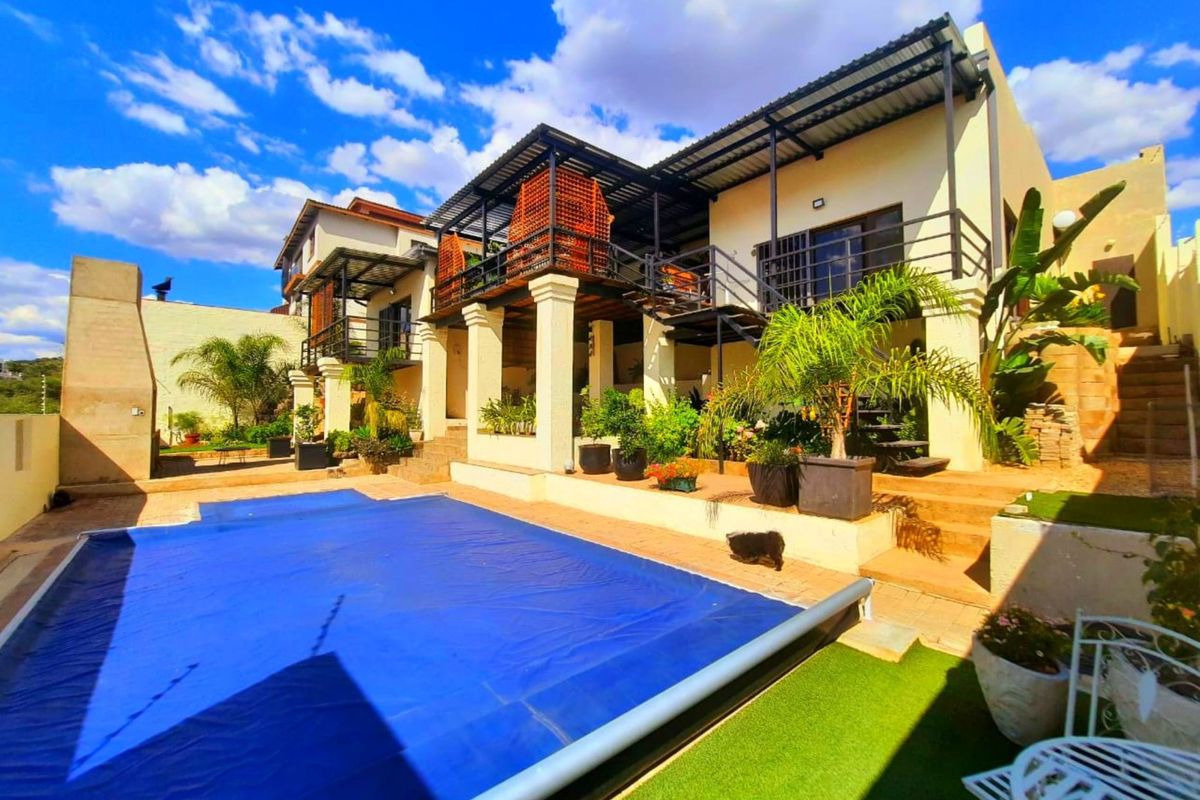 Rear exterior view featuring a swimming pool with a cover, raised patio area, and a multi-level balcony structure with metal stairs.
