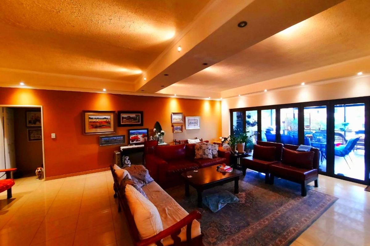 Spacious living room featuring tiled flooring, recessed downlighting, a bulkhead ceiling, and large bi-fold doors providing seamless access to the outdoor area.