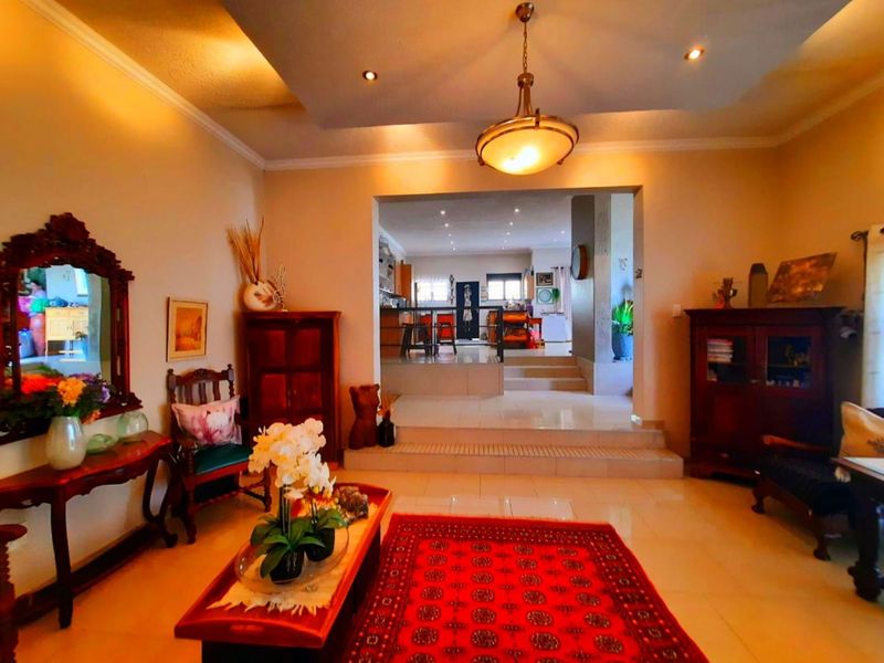 Spacious open-plan living area featuring a stepped transition to the kitchen, tiled flooring, and decorative recessed ceiling lighting.