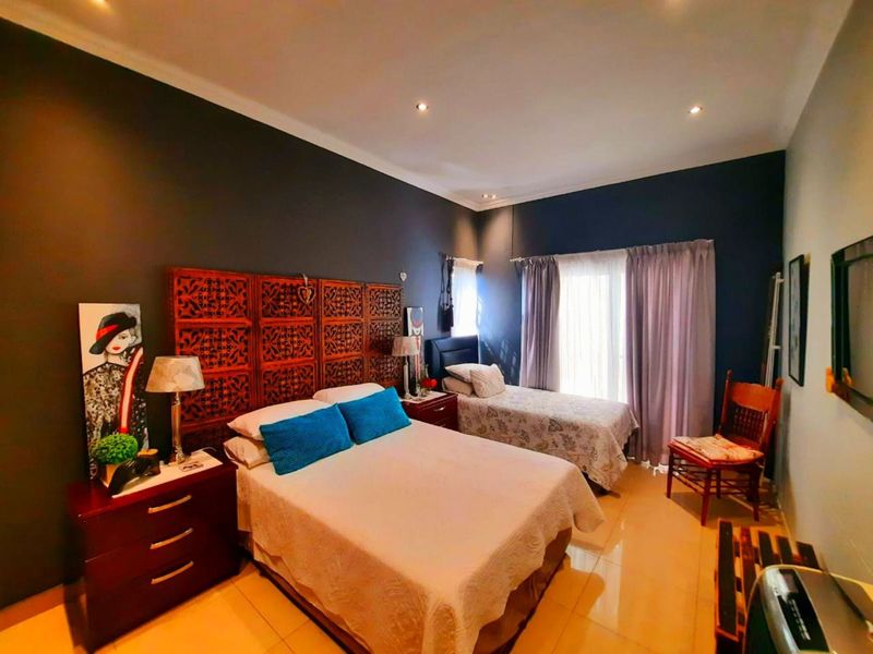 Spacious bedroom featuring tiled flooring, recessed downlighting, and a sliding glass door providing access to the exterior.