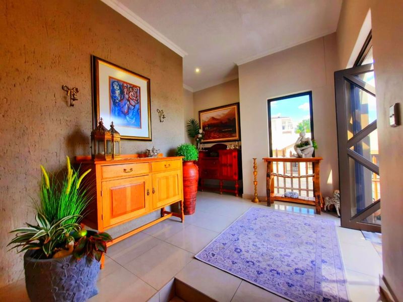 A welcoming entrance hall featuring tiled flooring, textured walls, and natural light from a large window, creating a bright and inviting transition space.