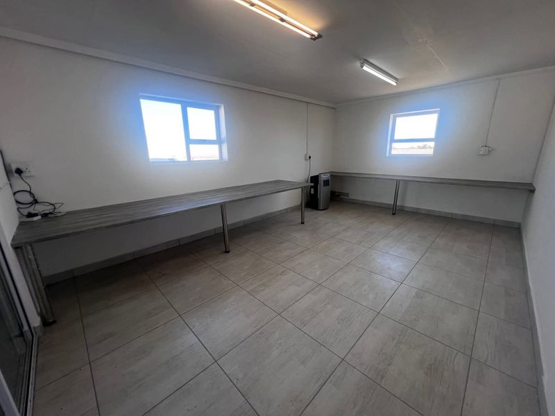 A clean, functional office space featuring built-in desks, tiled flooring, and ample natural light from dual windows.