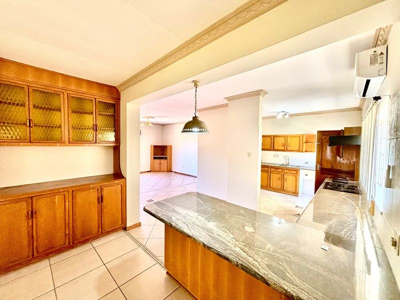 Spacious open-plan kitchen and living area featuring granite countertops, extensive wooden cabinetry, ceramic tile flooring, and a built-in gas hob.